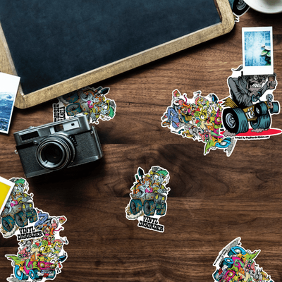 An assortment of promotional stickers displayed on a wooden surface alongside photography equipment