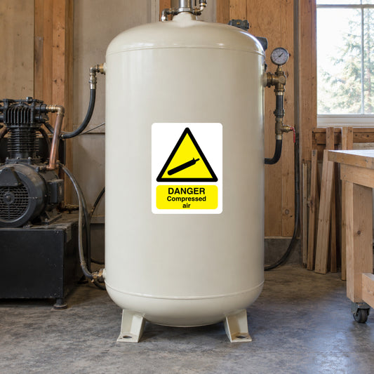 Danger compressed air warning sticker on a white pressure air tank, yellow and black sign