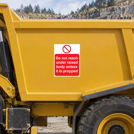 Safety warning sticker on yellow equipment: do not reach under raised body unless propped.