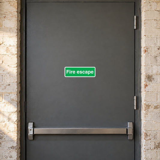 Green fire escape sign sticker with white “Fire escape” text on a dark door