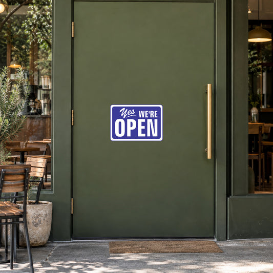 Sticker reading 'YES WE'RE OPEN' in blue on white