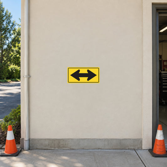 Yellow road sign sticker with black arrows pointing left and right