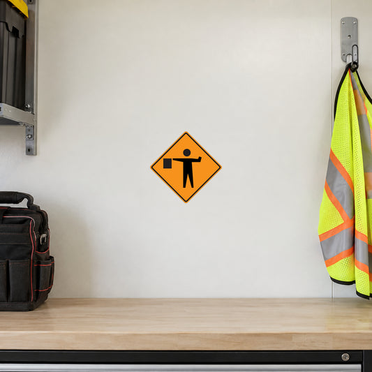 Road Sign Sticker applied in An ivory traffic crew storage wall with empty safety vest hook extreme right and closed toolbag left, blank smooth center