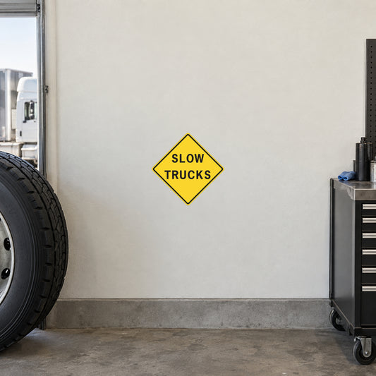 Road sign sticker with yellow diamond “SLOW TRUCKS” warning text