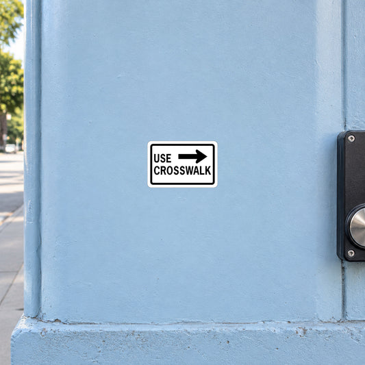 Road sign sticker with black "USE CROSSWALK" text and arrow icon