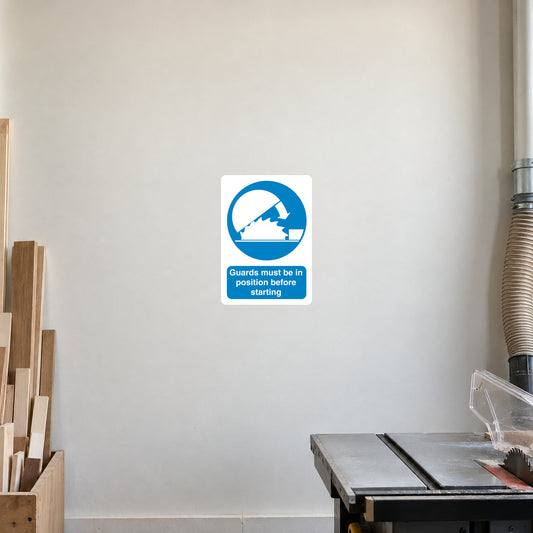 White square safety sign sticker with blue guard-in-position icon and text