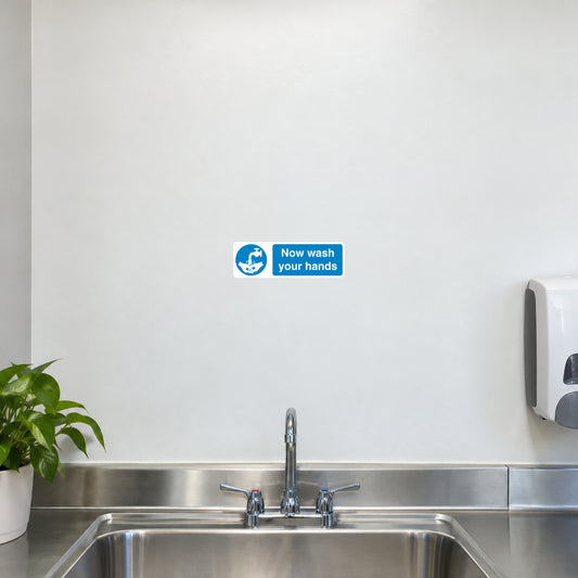 Safety Sign Sticker applied in a smooth white wall above a school kitchen handwashing basin, sink below y85 and soap dispenser far right, central clear