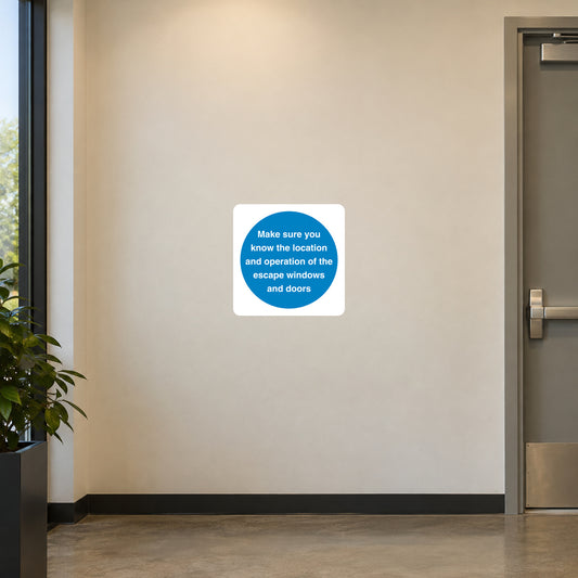 Safety Sign Sticker applied in a smooth warm cream wall in an office emergency escape briefing area, window frame at extreme left and closed exit door far right, centre clear