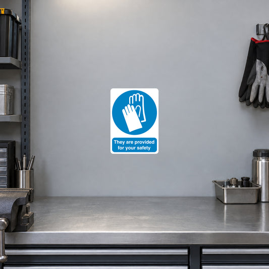 Safety Sign Sticker applied in a smooth light grey glove station wall beside a fabrication bench, protective gloves hanging extreme right and bench below y90