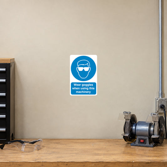 Safety sign sticker with blue goggles icon and text: “Wear goggles when using this machinery”