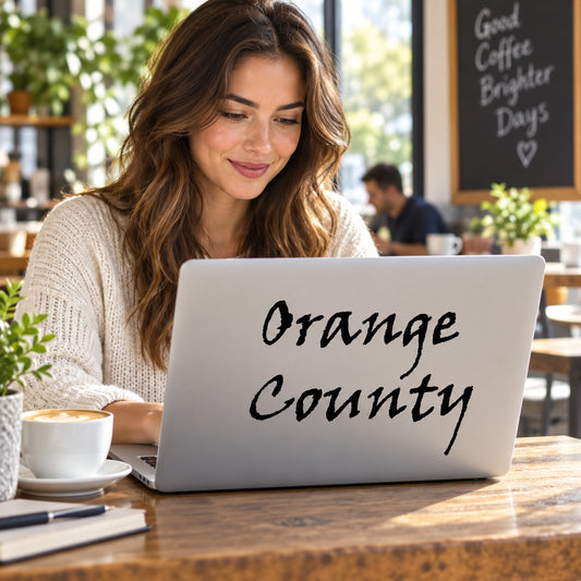Orange County decal-style text in black cursive on a laptop screen