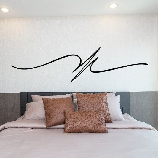 Black pinstripe script vinyl decal on the wall above a bed