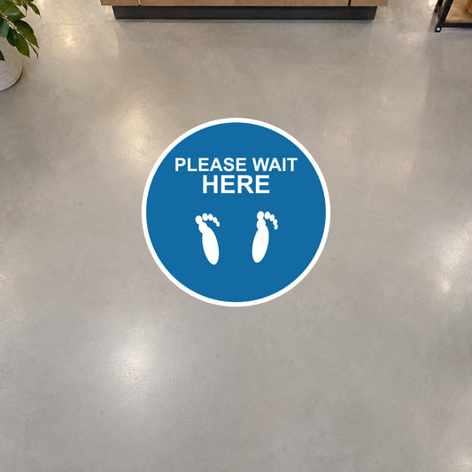 Round blue non-slip floor sticker reading “PLEASE WAIT HERE” with white foot icons