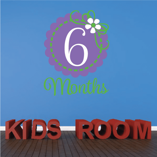 Purple 6-month wall decal with flower and green text, plus KIDS ROOM letters