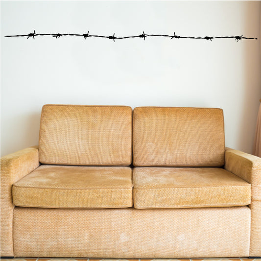 Barbed wire wall decal strip with pointed barbs and crossed metal loops, black.