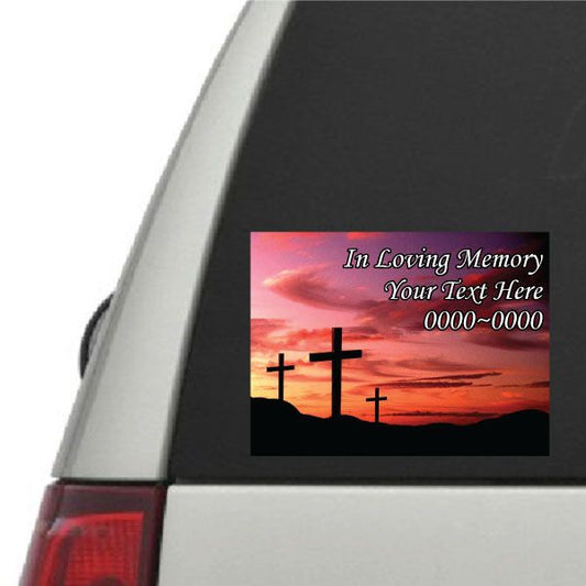 Memorial rectangle sticker with pink sunset sky, black field, and three black crosses
