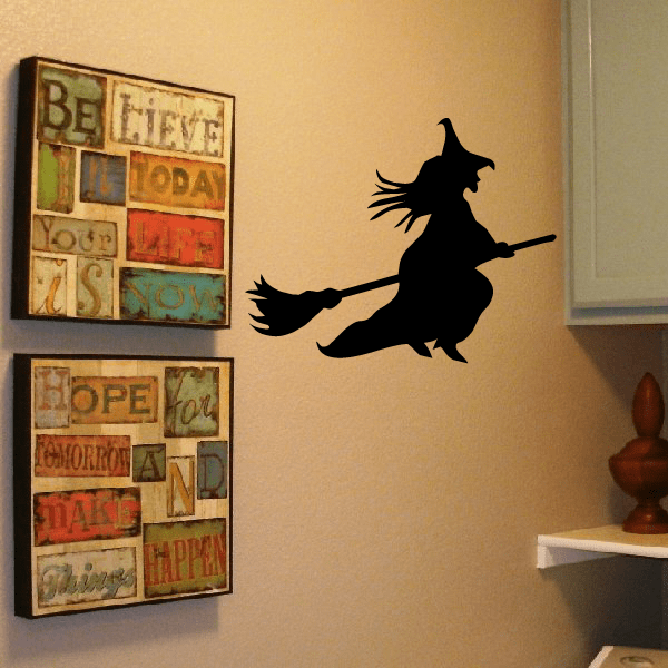Flying witch silhouette decal on a broom, black cutout style.