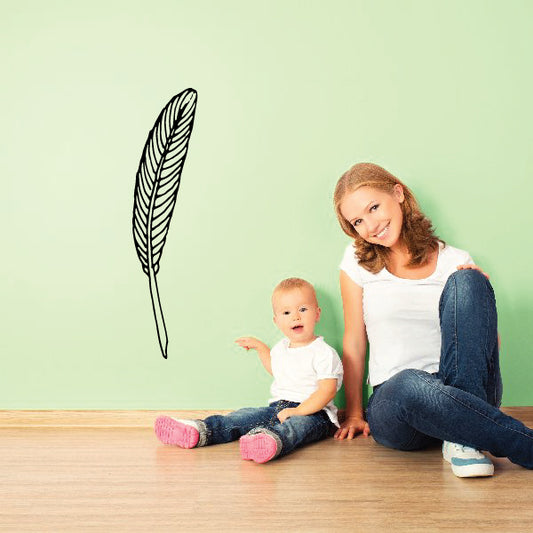 Feather wall decal of a single black quill on a light background