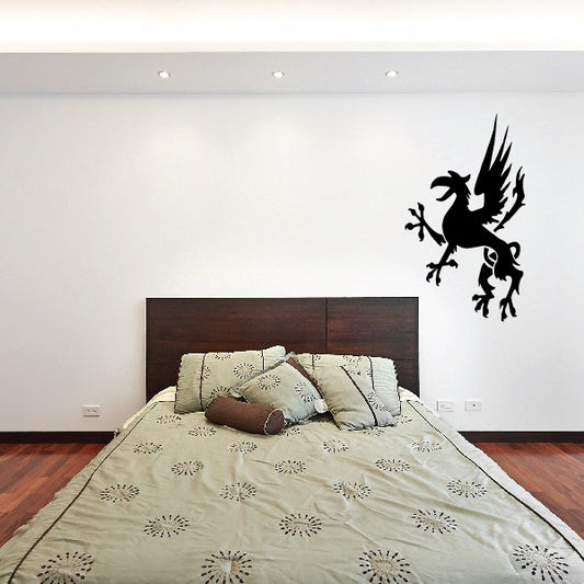 Black griffin wall decal with wings spread above a bed