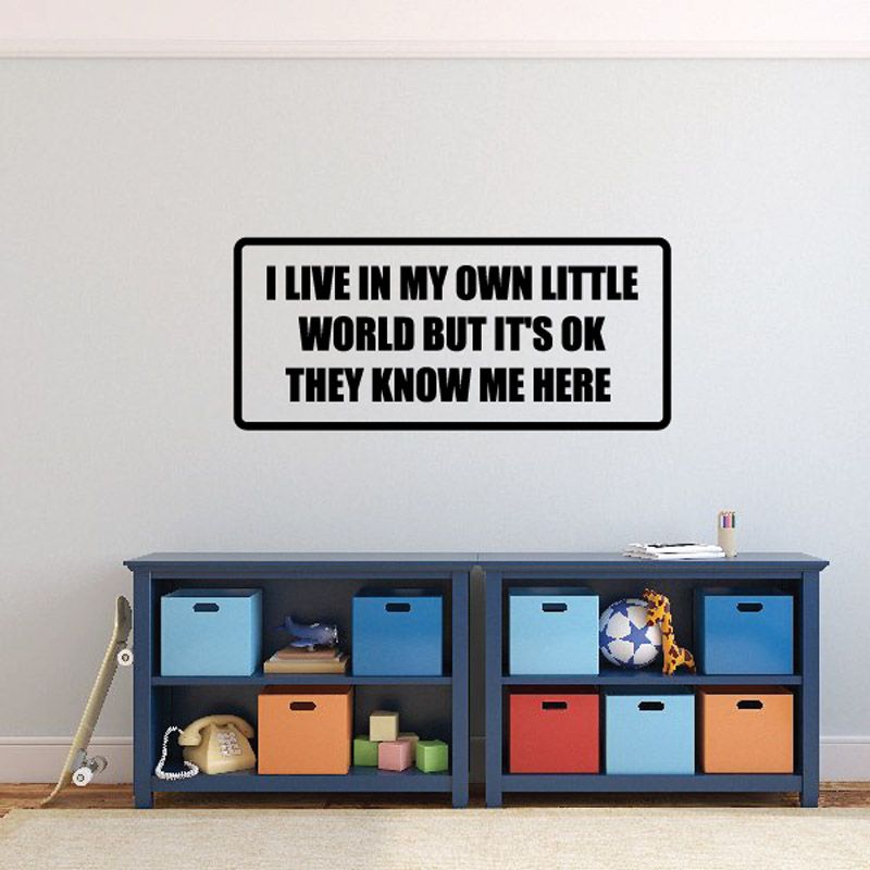 Wall quote decal with black border and bold white text, “Live in my own little world…”