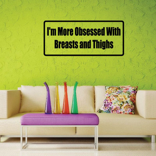 Rectangular wall decal with black border and bold text reading “I'm More Obsessed With Breasts and Thighs”