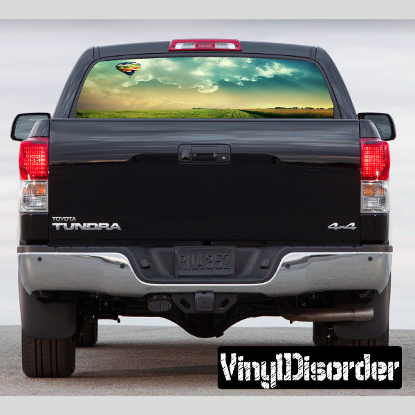 Pickup rear window graphic decal with landscape scene, dark trim around glass