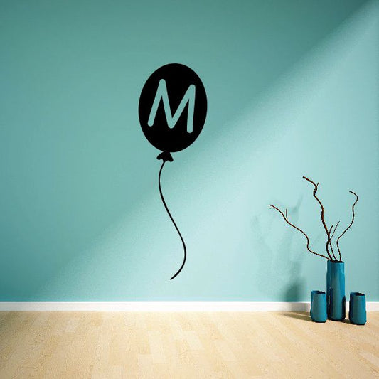 Letter M balloon wall decal with black balloon and green M, curly string