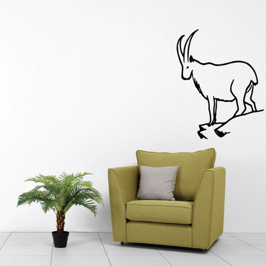 Black mountain goat decal standing on a ledge above an armchair