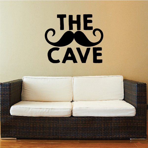 Black wall decal reading "THE CAVE" with curled mustache icons