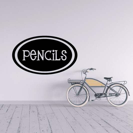 Oval pencils wall decal with black outline and white lettering, says PENCILS