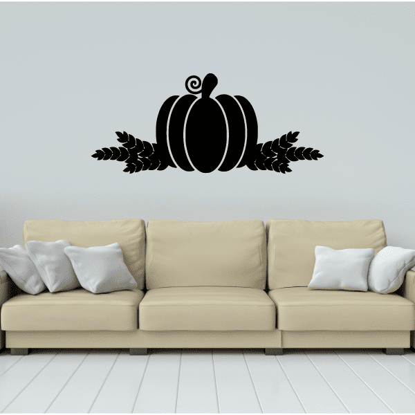Black pumpkin with wheat decal on wall above a light sofa