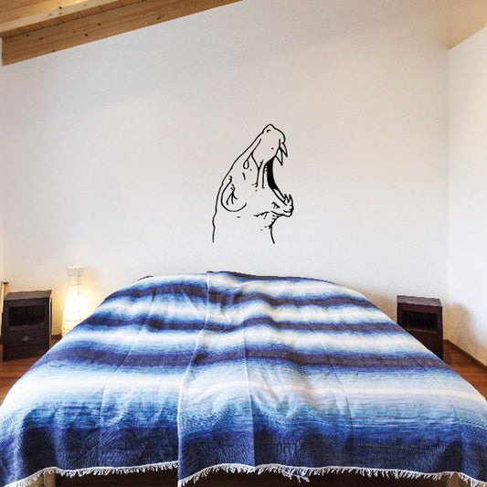 Roaring bear head decal in black line art on a wall above a bed