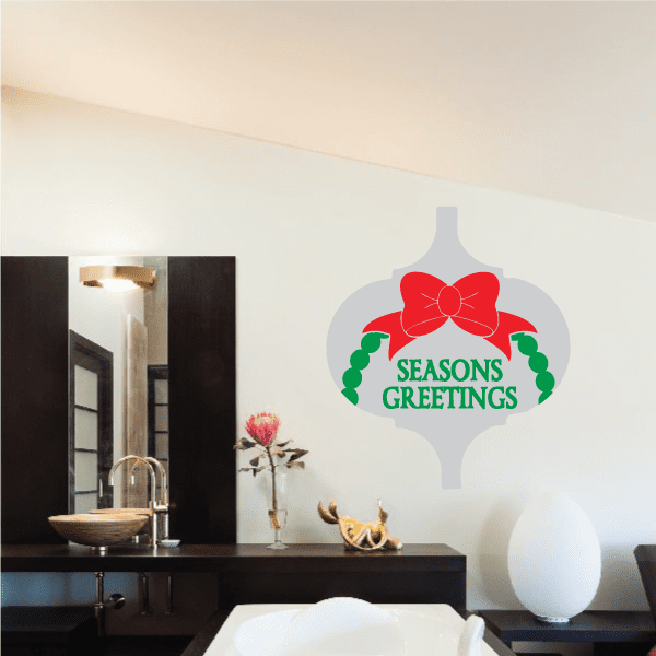 Seasons Greetings ornament sticker with white shape, red bow and green wreath, text