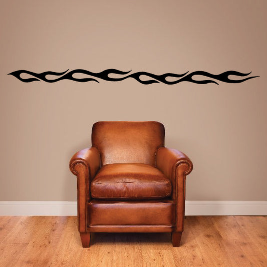 Black flame wall decal strip above a brown leather armchair.