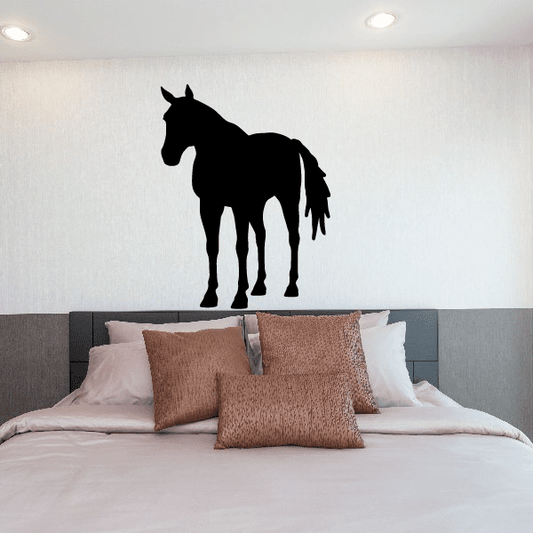 Black standing horse silhouette decal on a wall above a bed