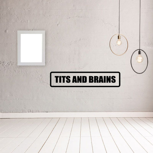 Wall decal with black rectangle border and bold “TITS AND BRAINS” text