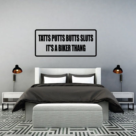 Rectangular wall decal with black border and bold text: 'Tatts Putts Butts Sluts'.