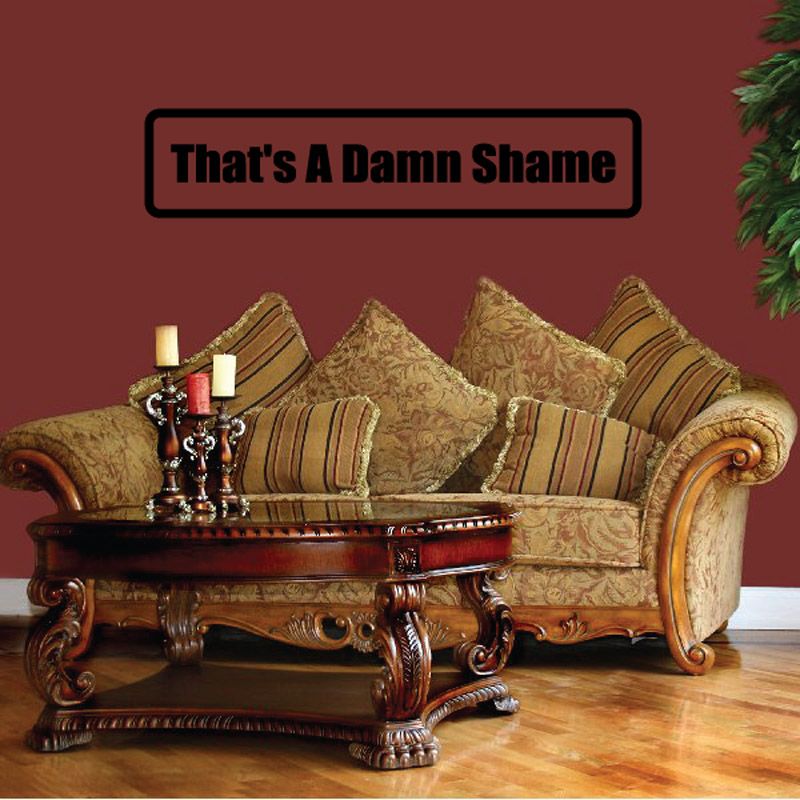 Wall decal: 'That's A Damn Shame' in bold black on tan rectangle