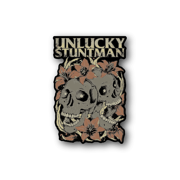 Vinyl sticker with Unlucky Stuntman text, twin skulls and leaves, tan.