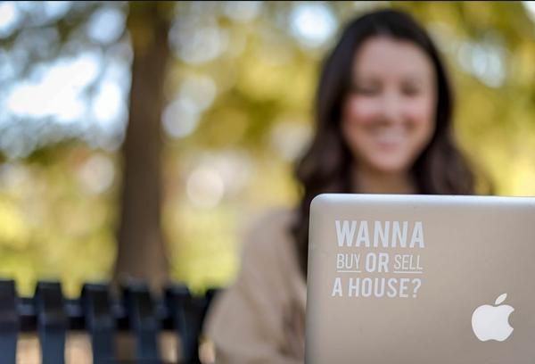 Closed laptop lid with printed real-estate slogan and Apple logo