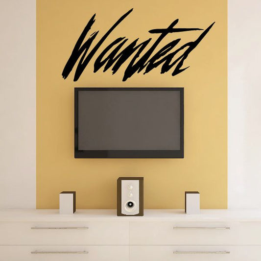 Wanted decal with bold black brush-script lettering on a wall