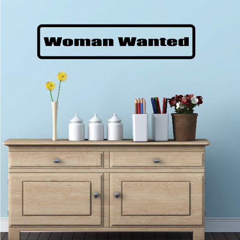Wall decal with bold "Woman Wanted" text in black and white border