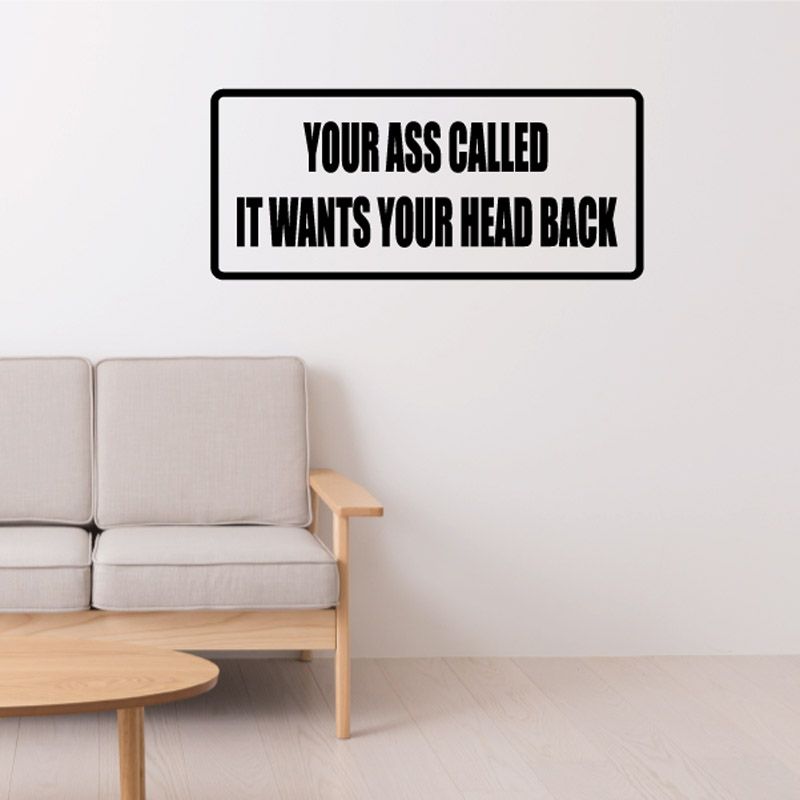 Wall decal with black text inside border: YOUR ASS CALLED IT WANTS YOUR HEAD BACK
