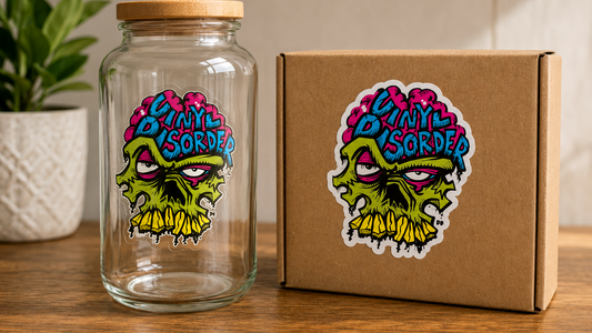 Clear sticker on glass bottle beside white vinyl sticker on kraft package using the same Vinyl Disorder skull artwork