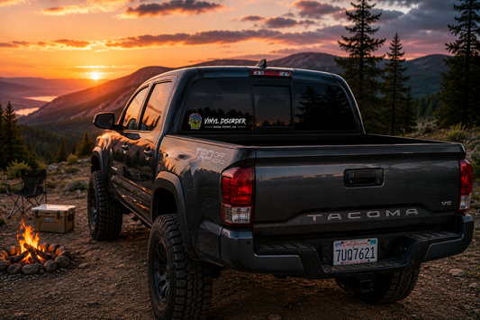 Custom Vinyl Disorder truck window decal on a black pickup at a sunset campsite