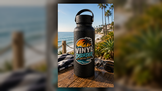 Waterproof vinyl sticker on black water bottle with water droplets near the ocean