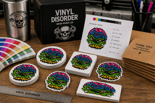Round, oval, square, rectangle, and custom die cut Vinyl Disorder sticker samples arranged on a print shop worktable