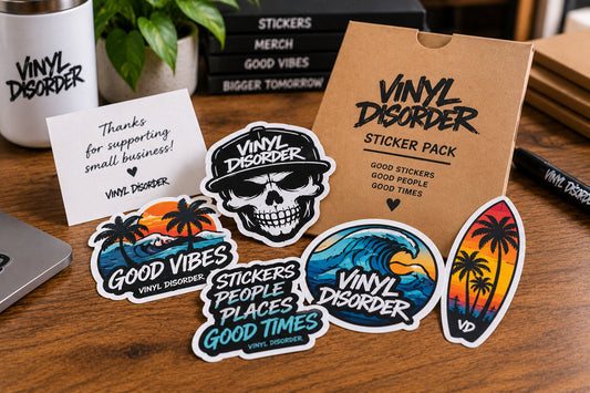 Branded Vinyl Disorder sticker pack fanned out on a wood table with kraft packaging