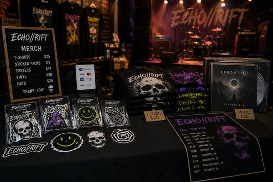 Fictional band merch table with custom sticker packs, shirts, vinyl records, posters, hats, pricing, and warm stage lighting