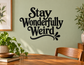 Black vinyl wall decal reading “Stay Wonderfully Weird” with swoosh underline